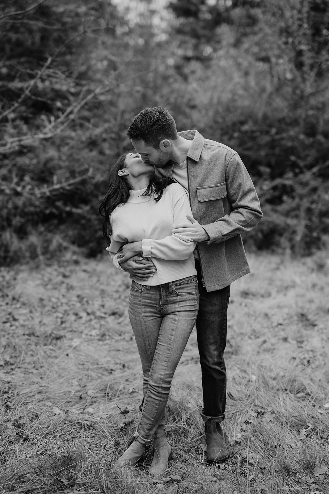 Couple kissing in front of red holly bushes during fall at Discovery Park.