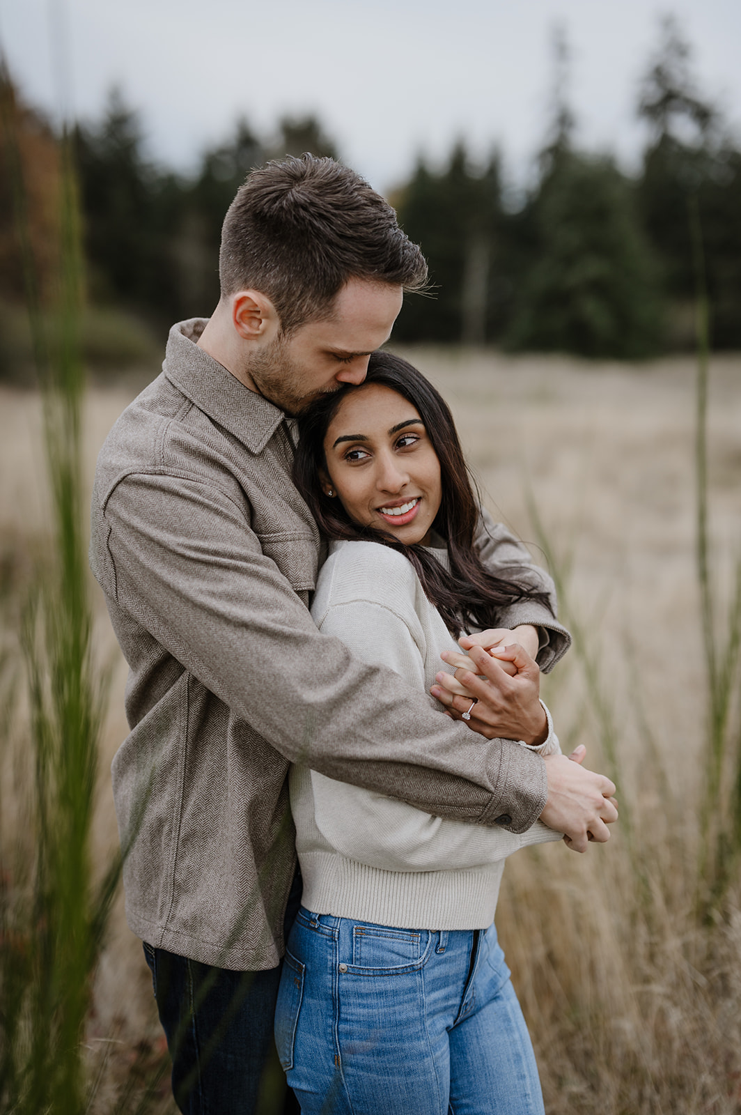 Couple sharing an intimate moment, embracing each other in a fall field at Discovery Park.