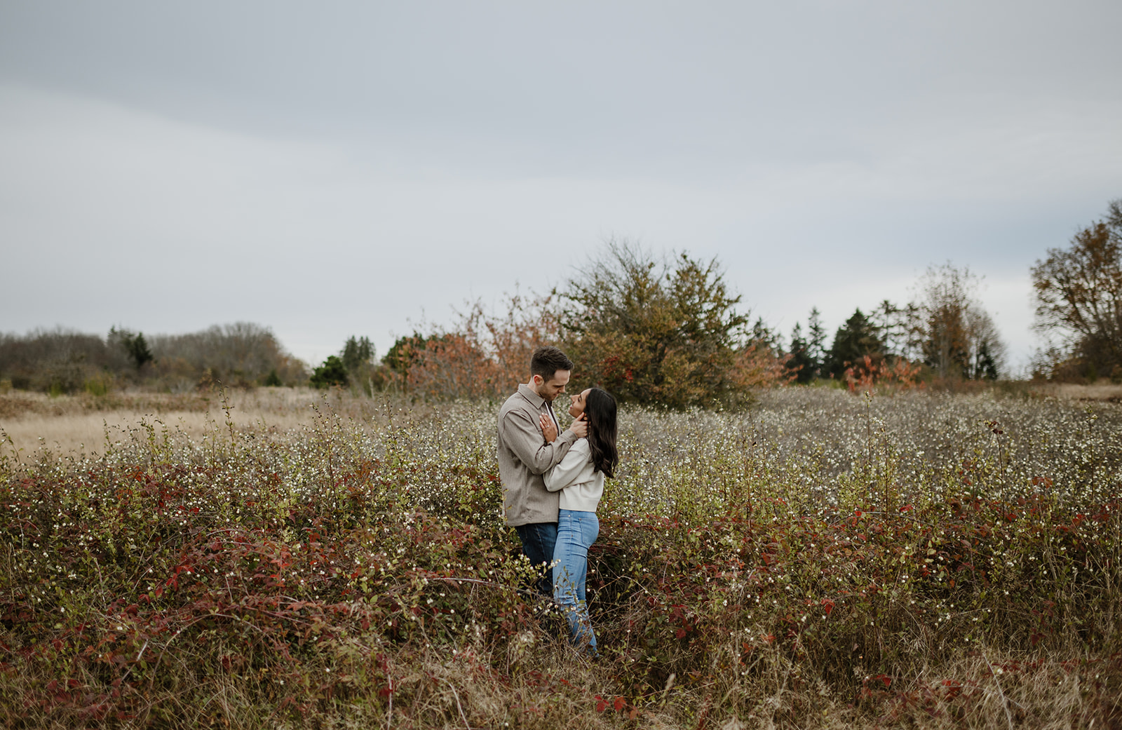 Couple standing close together in a field of wildflowers at Discovery Park during fall.