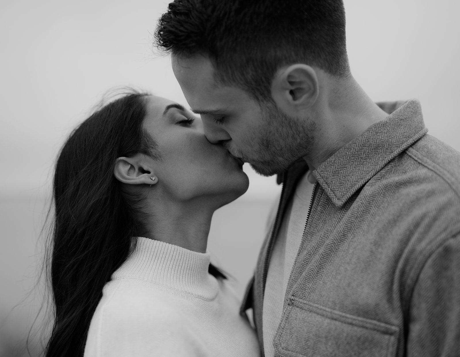 A close-up shot of a couple leaning in for a kiss, surrounded by a soft, misty atmosphere.