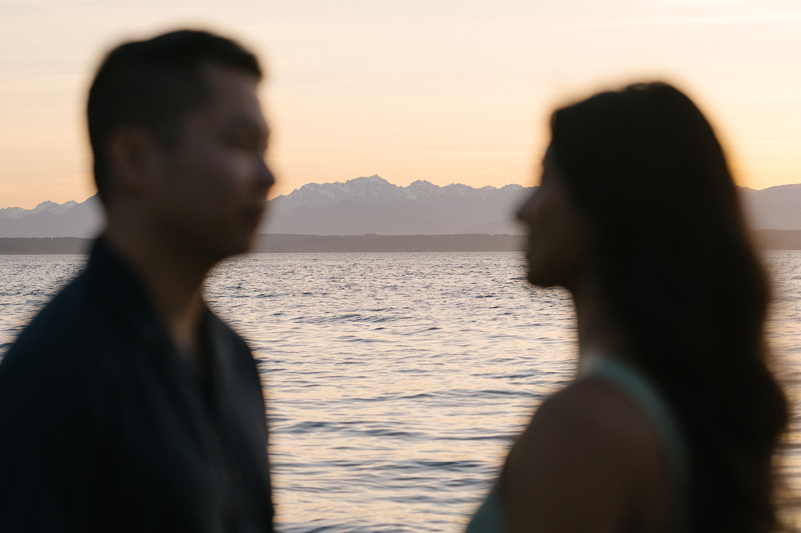 A couple holding hands and walking along the rocky beach at Carkeek Park.