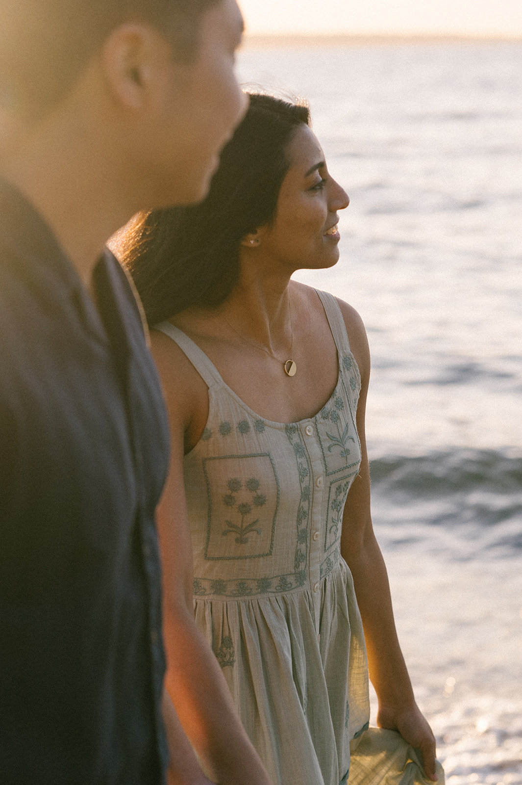 A couple walking along the beach at sunset, hand-in-hand.