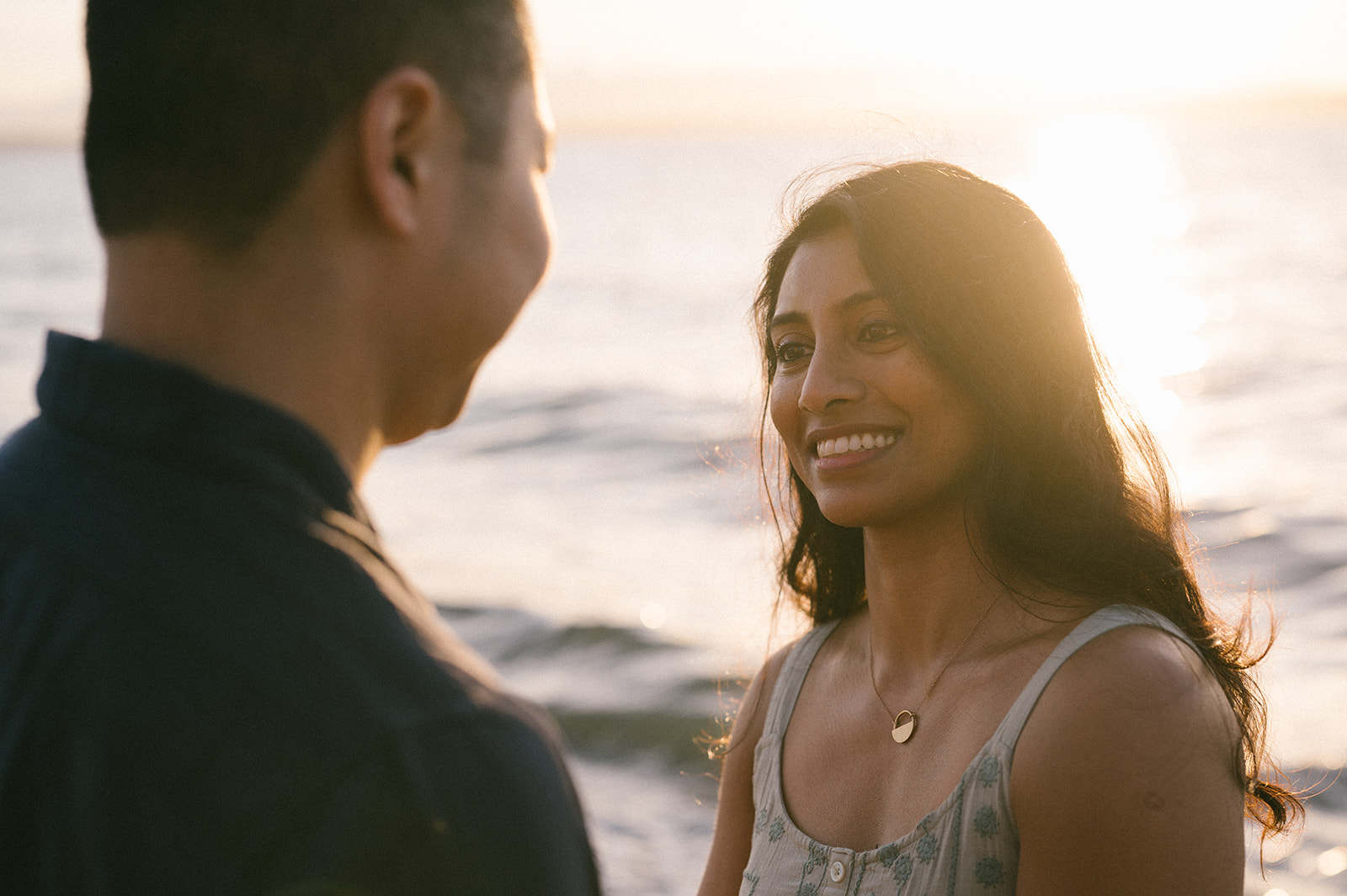 A woman smiling at her partner with the sun setting behind them.