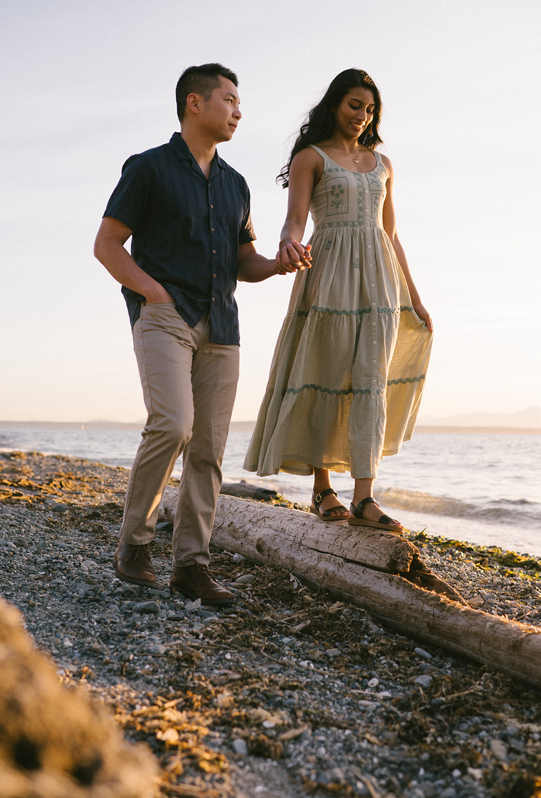 A couple walking hand-in-hand along the beach at sunset.