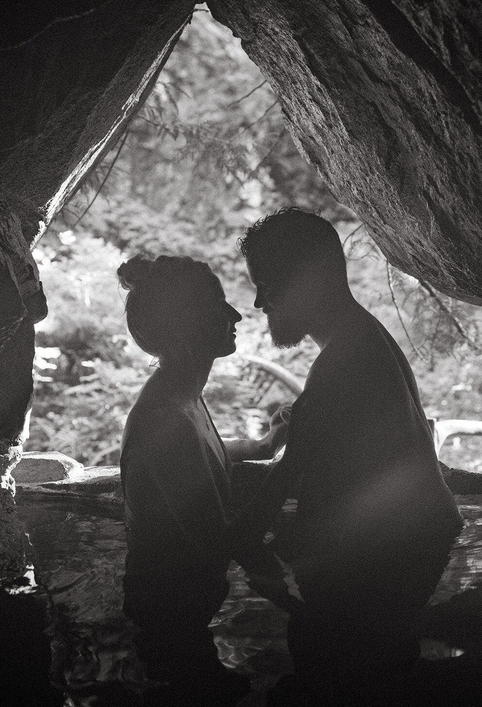 Black and white silhouette of R and M in a cave hot spring.