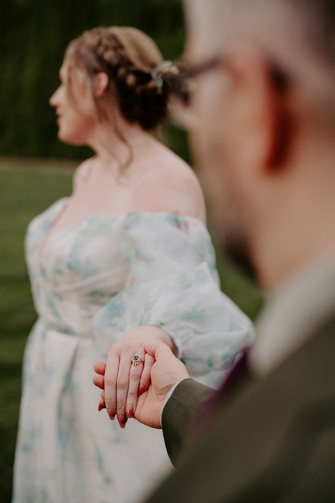 Close-up of couple holding hands with focus on a unique gemstone ring