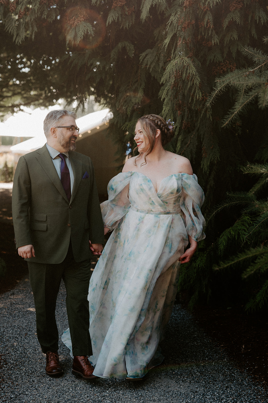 Couple standing hand in hand beneath dramatic evergreens
