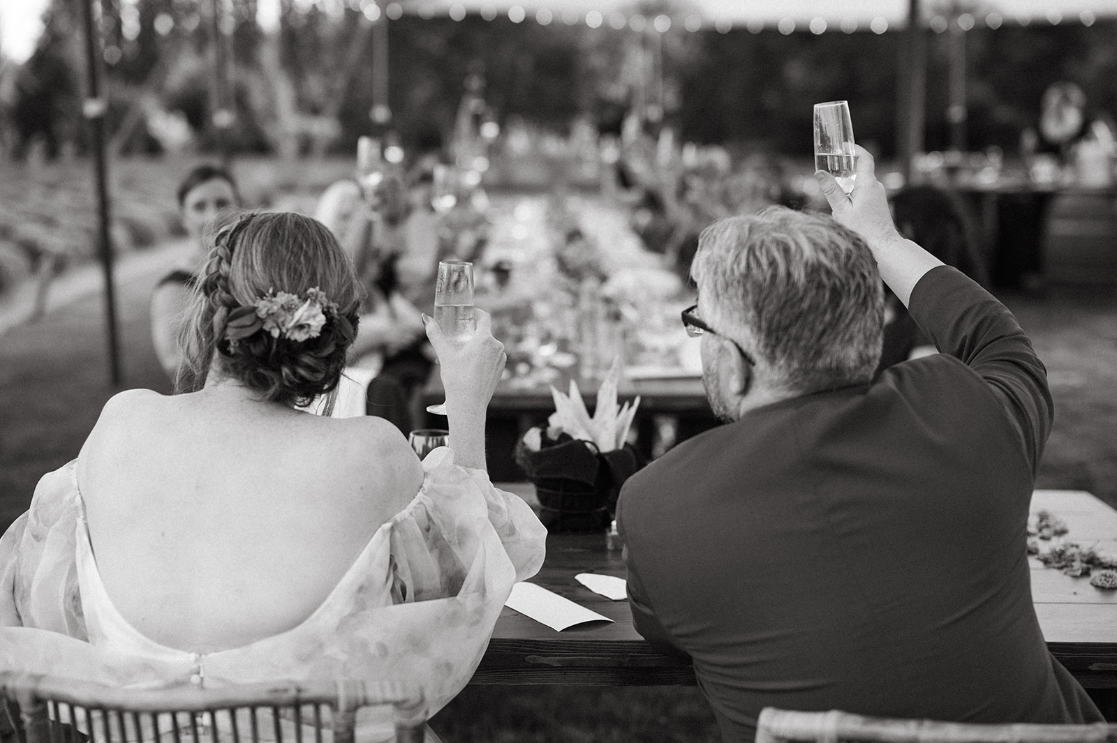 Couple raising glasses to guests during evening wedding toast