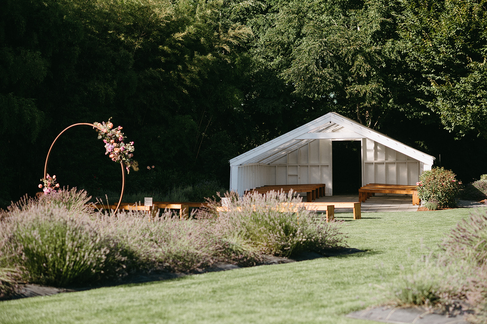 White open-air structure and floral arch in lavender field setting