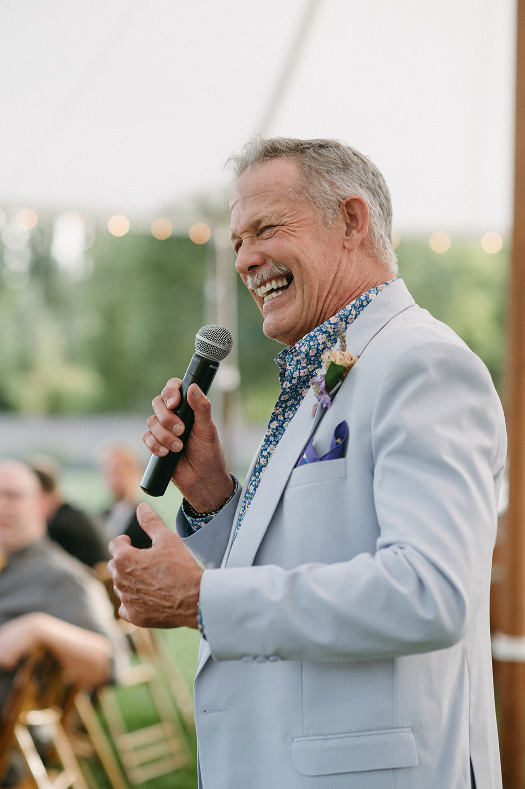 Father of the bride giving toast with a big smile under the tent