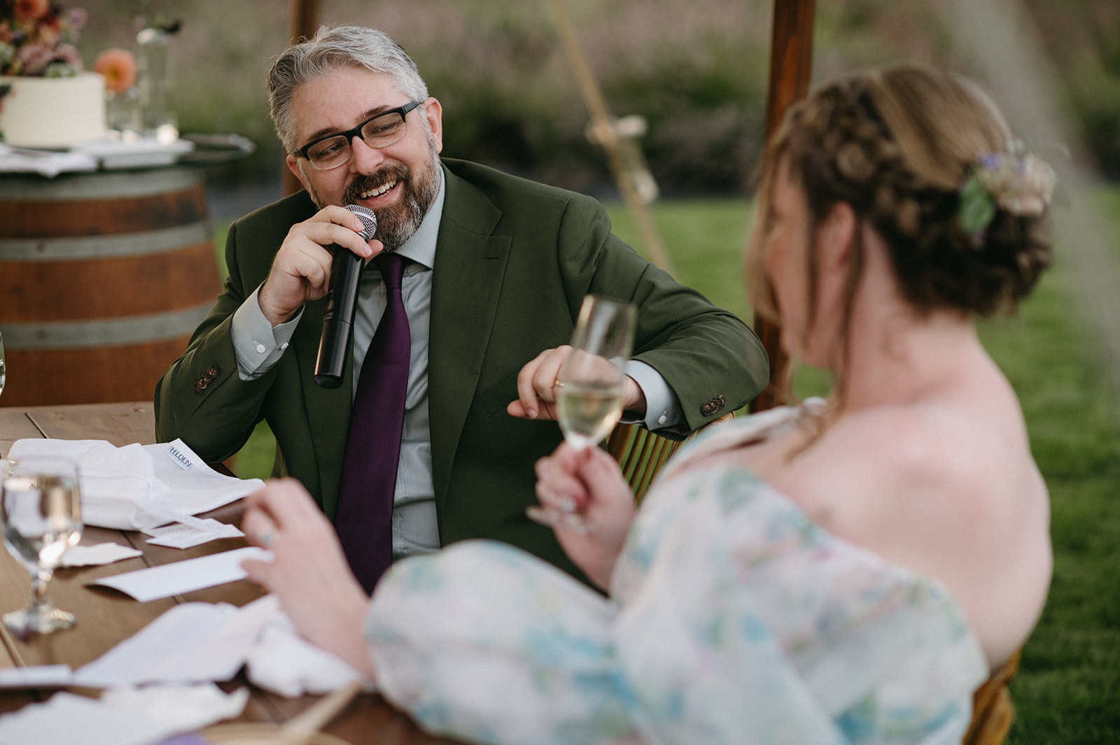 Groom holding microphone and smiling at partner during reception