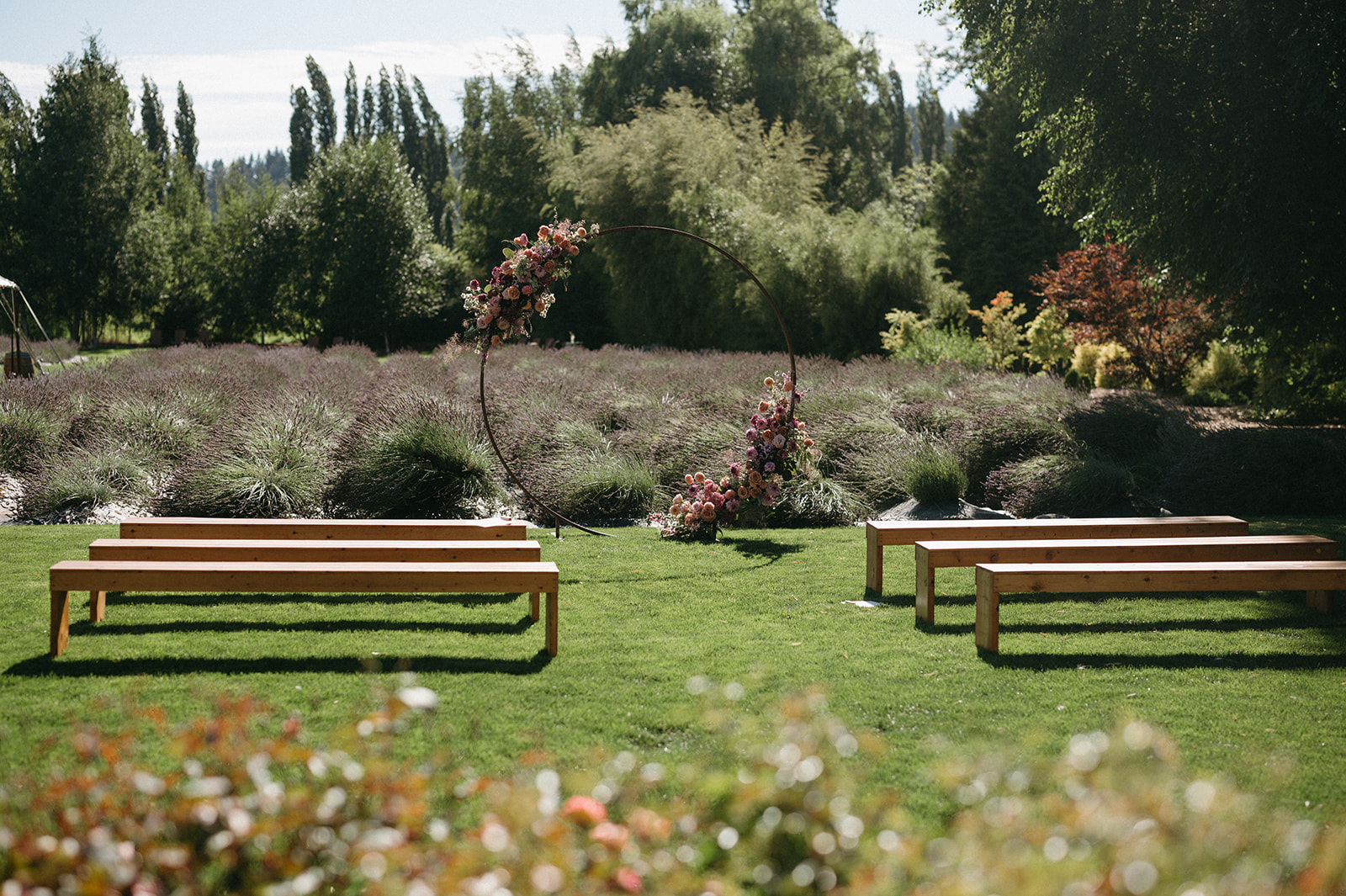 Circular floral ceremony arch framed by lavender and empty benches