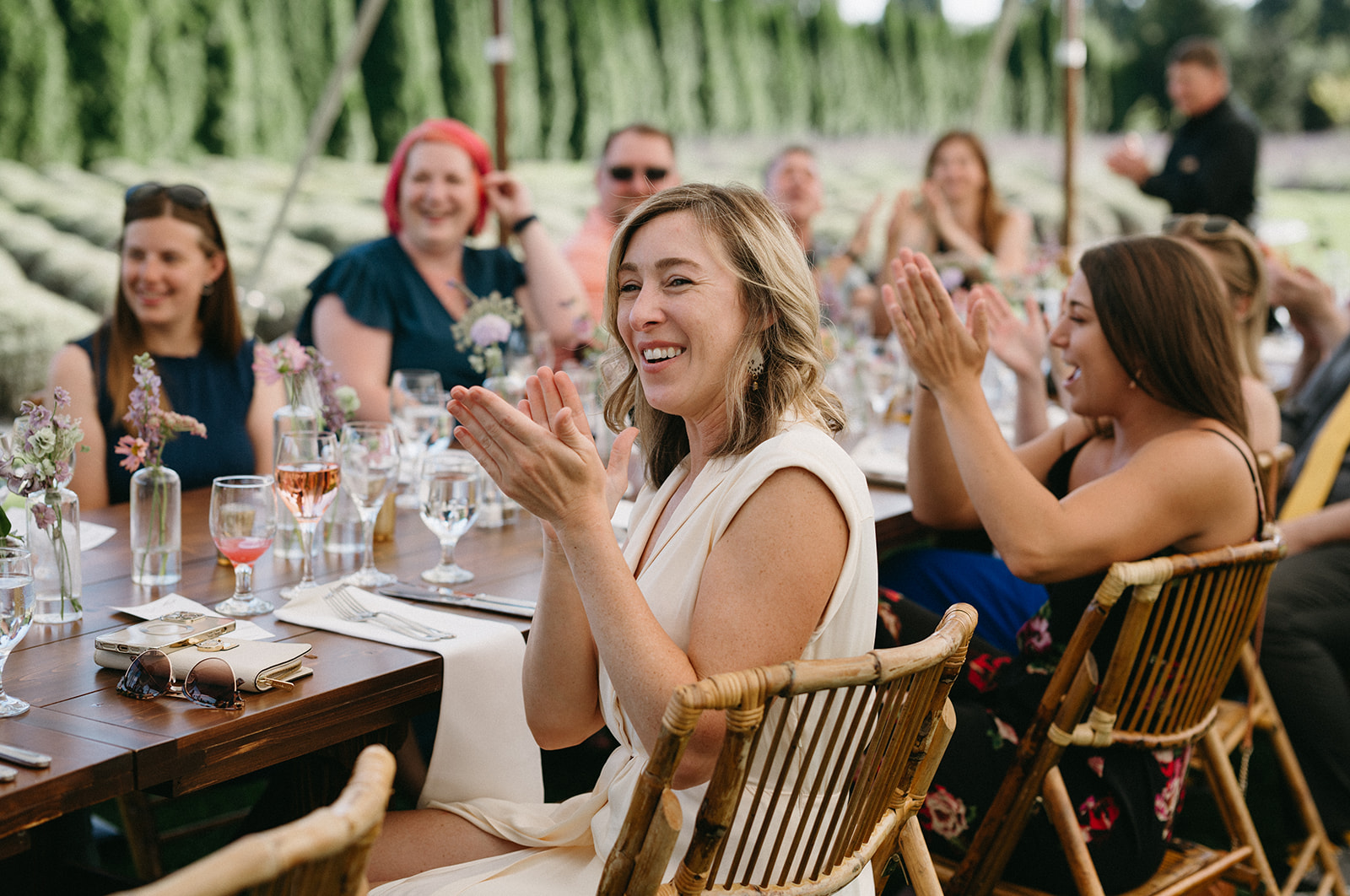 Guests clapping and smiling at long table during wedding dinner