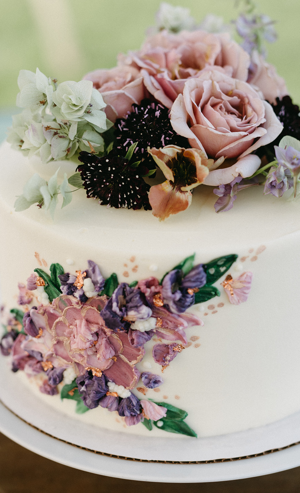 Close-up of wedding cake topped with fresh roses and other florals.