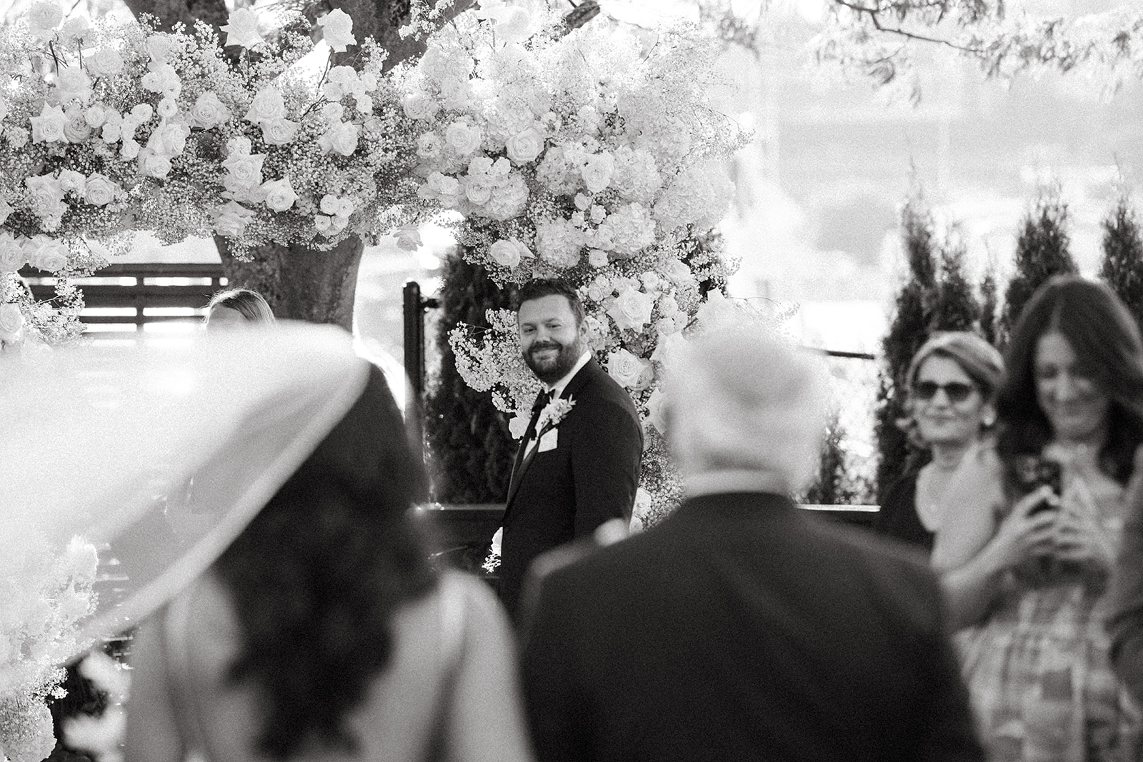 Groom smiling as he watches the bride walk down the aisle at a Dockside at Duke’s wedding.