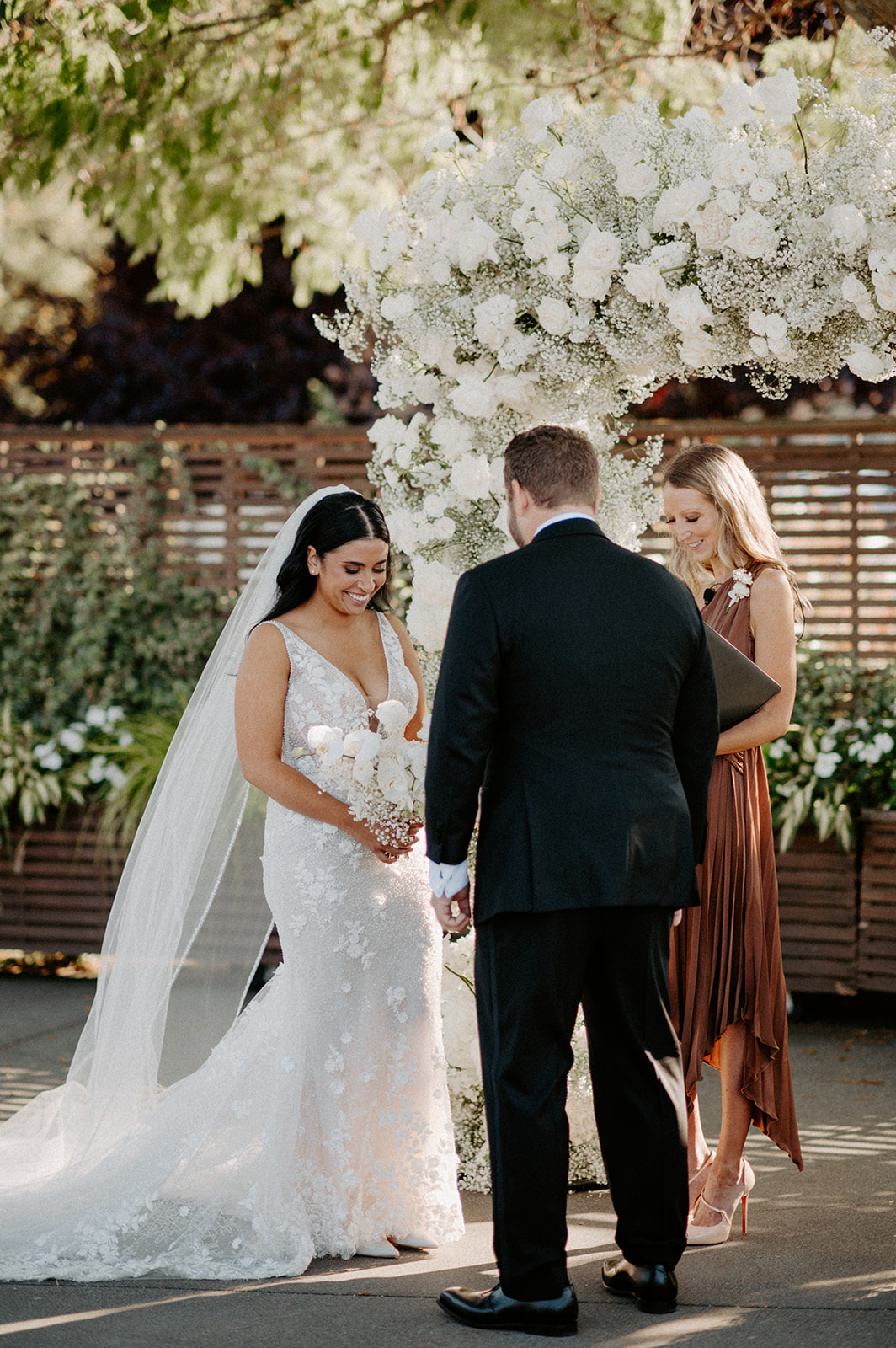 Bride and groom exchange vows under a floral arch during their wedding at Dockside at Duke’s.