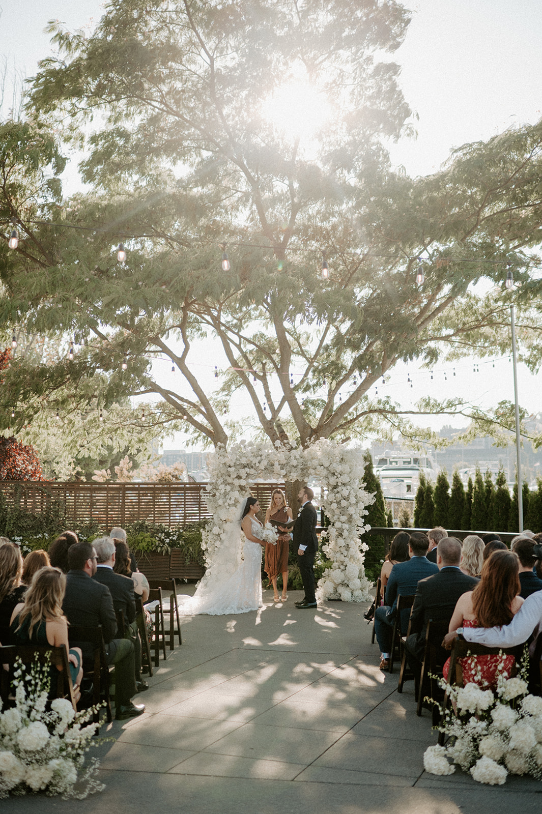 Bride and groom exchanging vows under a floral arch at Dockside at Duke’s wedding ceremony.