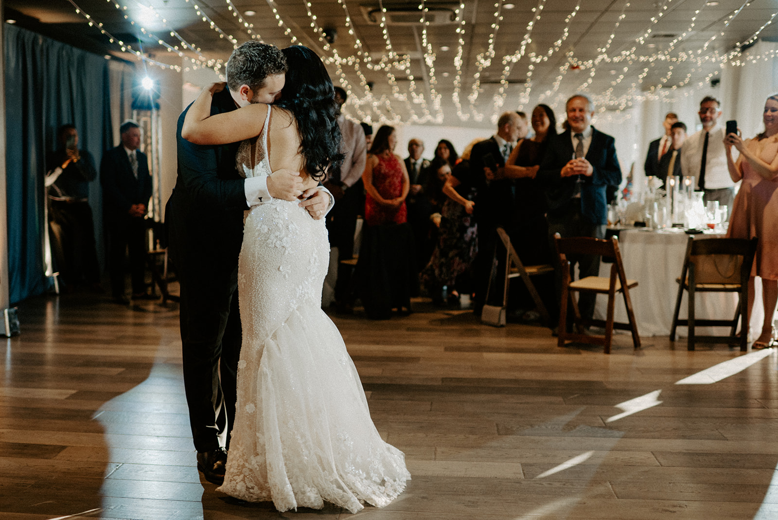 Bride and groom share an intimate first dance under string lights at their wedding reception.