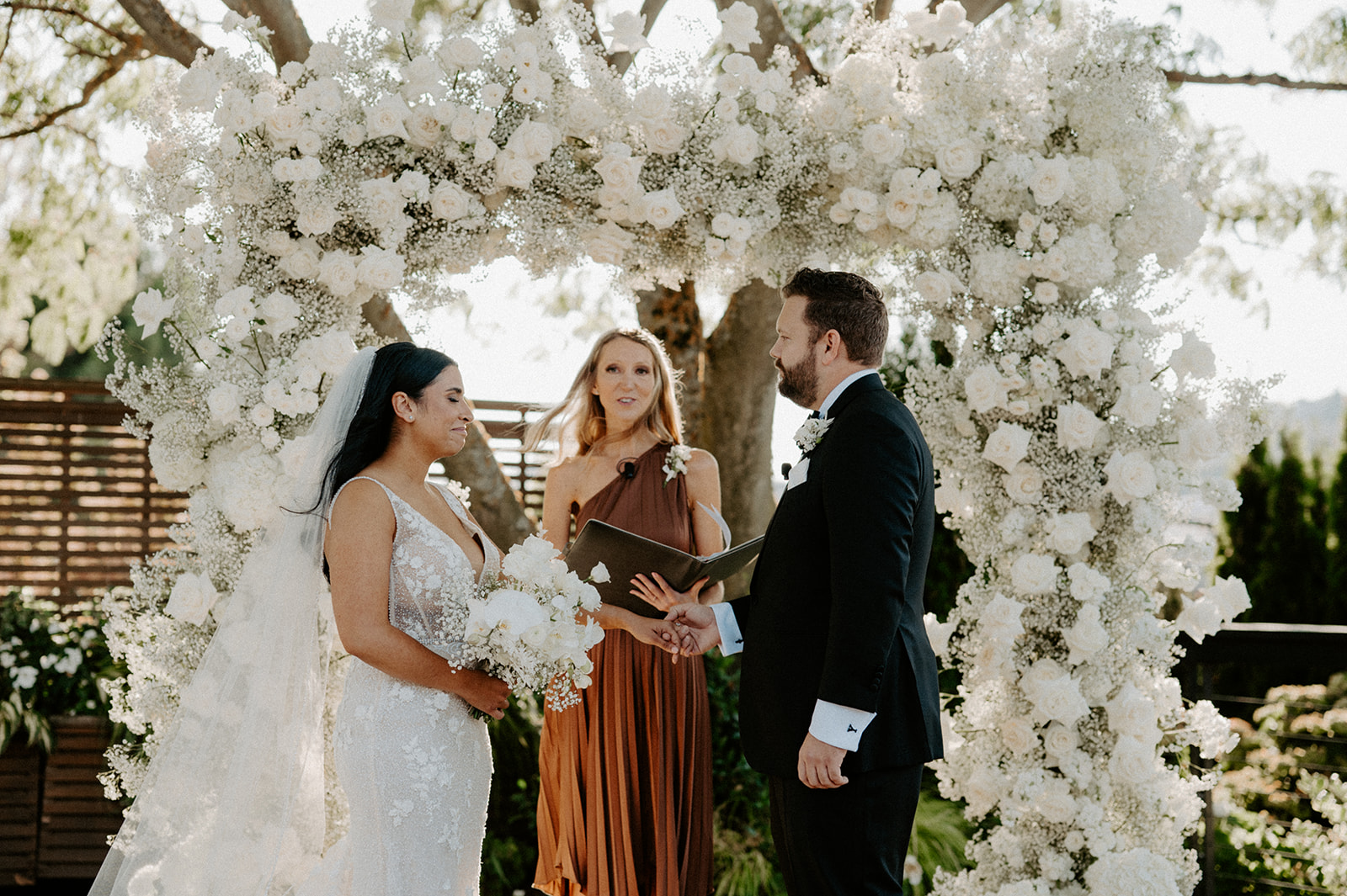 Bride and groom standing under a floral arch during their Dockside at Duke’s wedding ceremony.