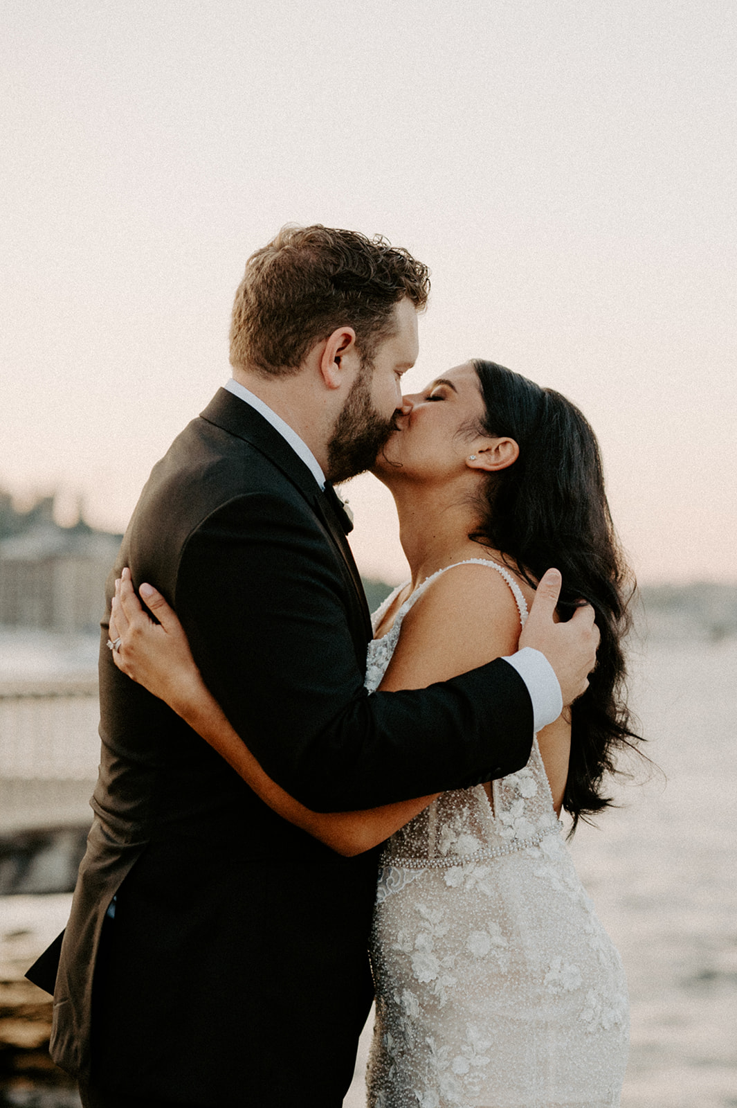 Bride and groom sharing a kiss on a dock with the water and Seattle skyline in the background.