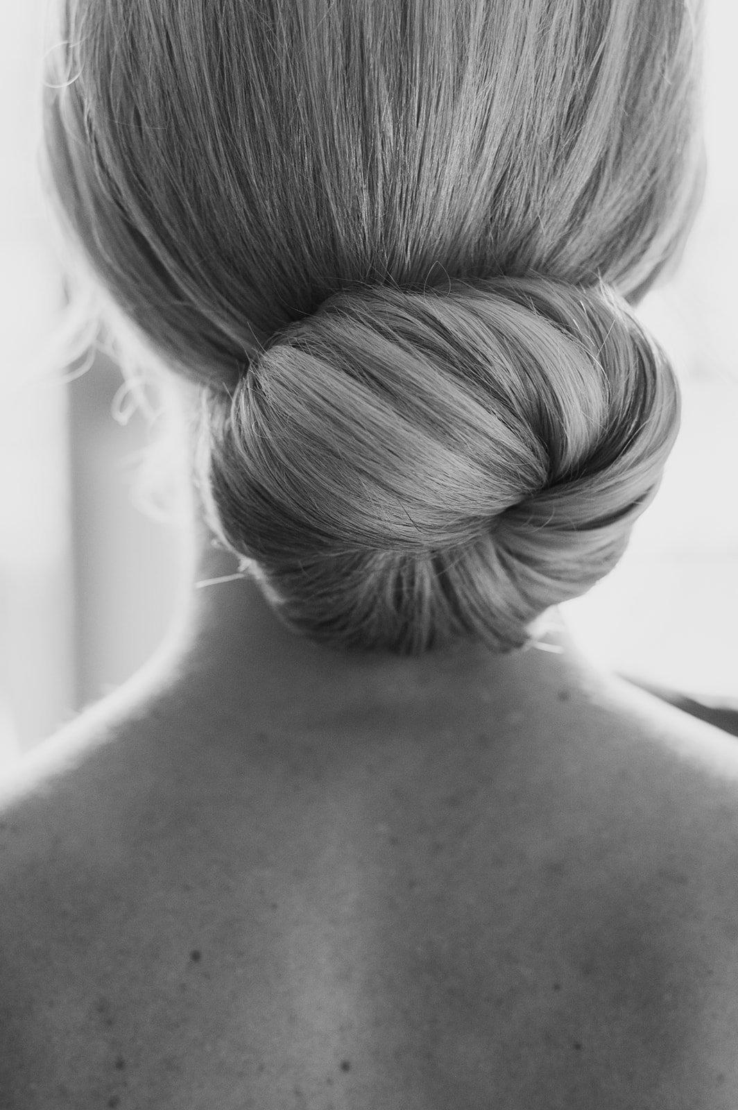 Black and white portrait of the back of the bride’s low bun hairstyle.
