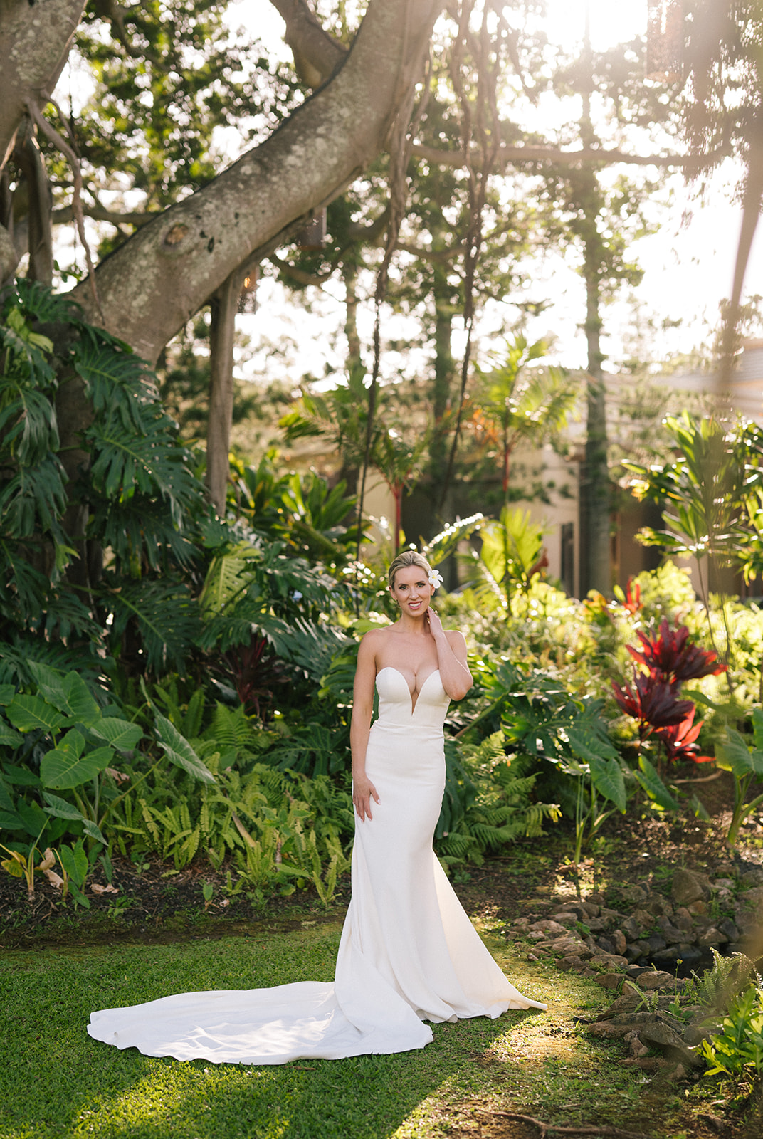 Full-length portrait of the bride in her wedding dress standing in a lush tropical garden in Kapalua, Maui.
