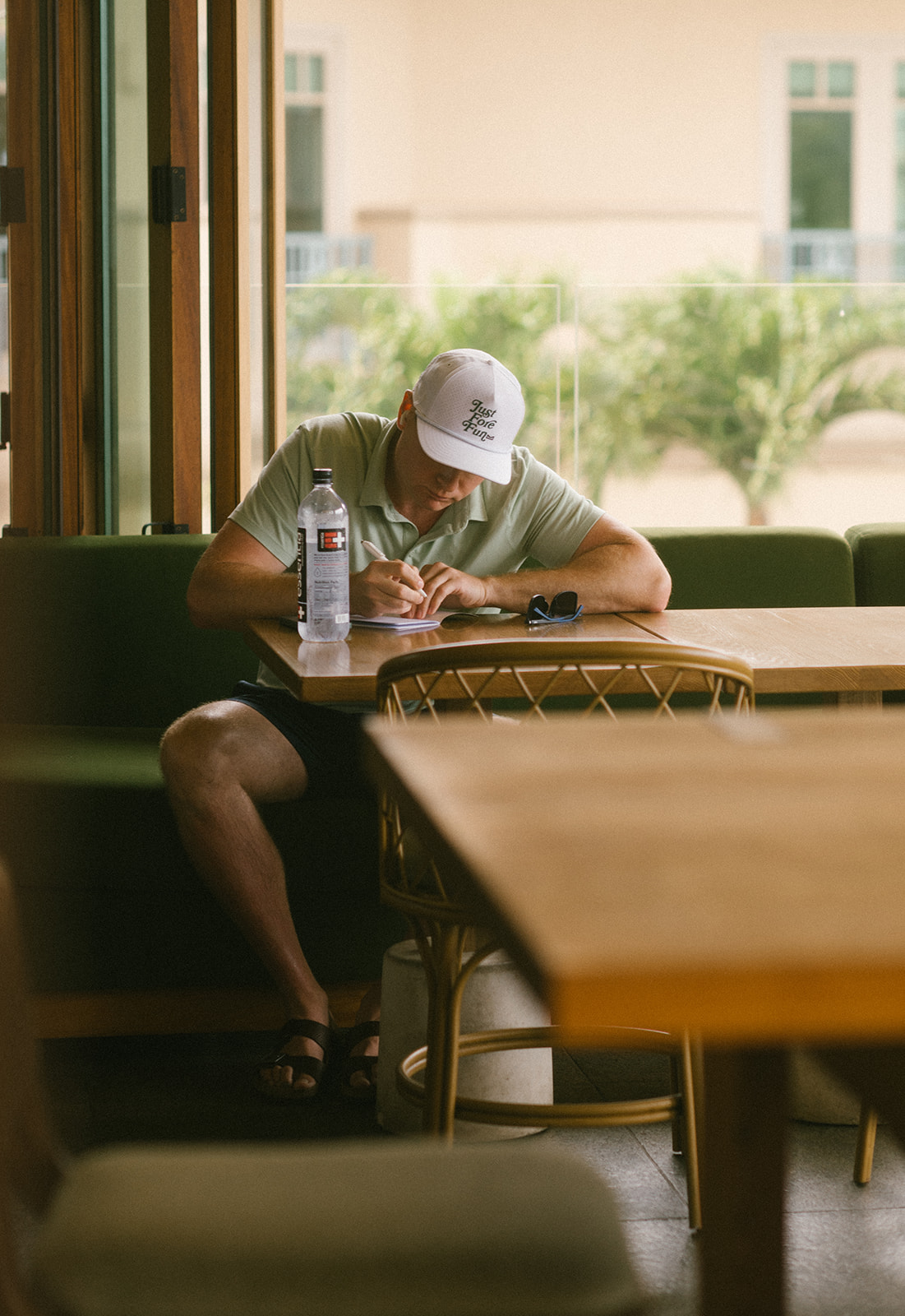 Groom sitting at a table writing his vows in a notebook inside his hotel room in Maui.
