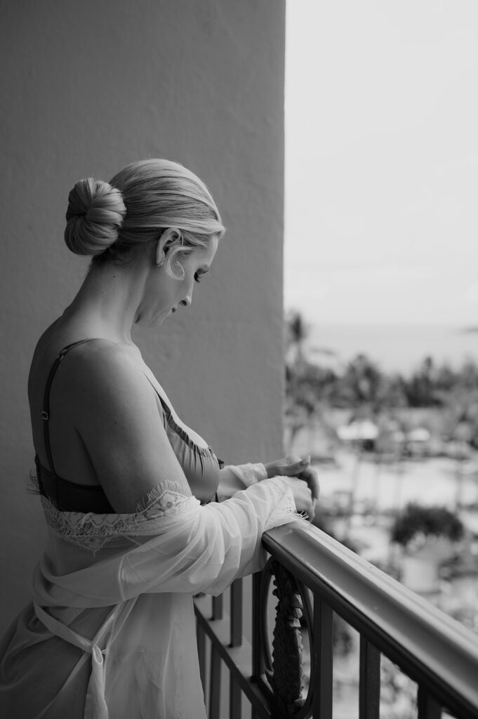 Black and white photo of the bride standing on her balcony at the Four Seasons Maui, looking out toward the ocean.
