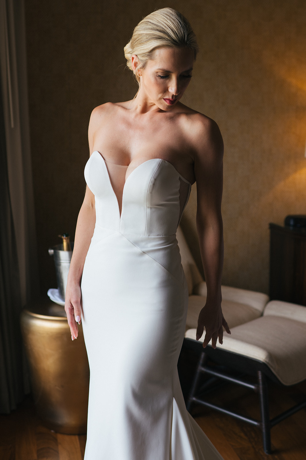 Bride standing in her fitted white wedding dress in soft light inside her Four Seasons Maui suite.
