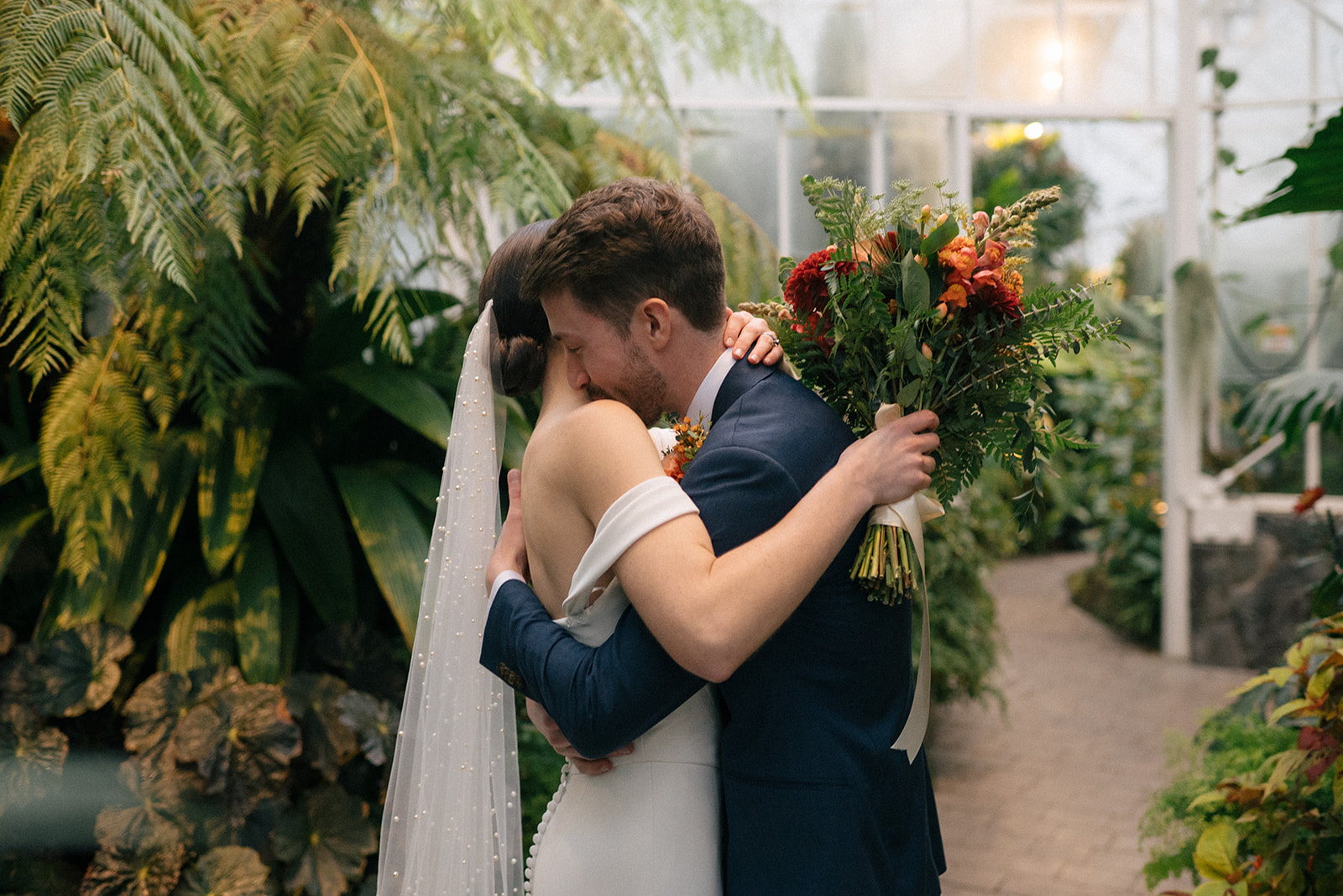 Taylor and Patrick embracing in an emotional moment with her holding a vibrant bouquet.