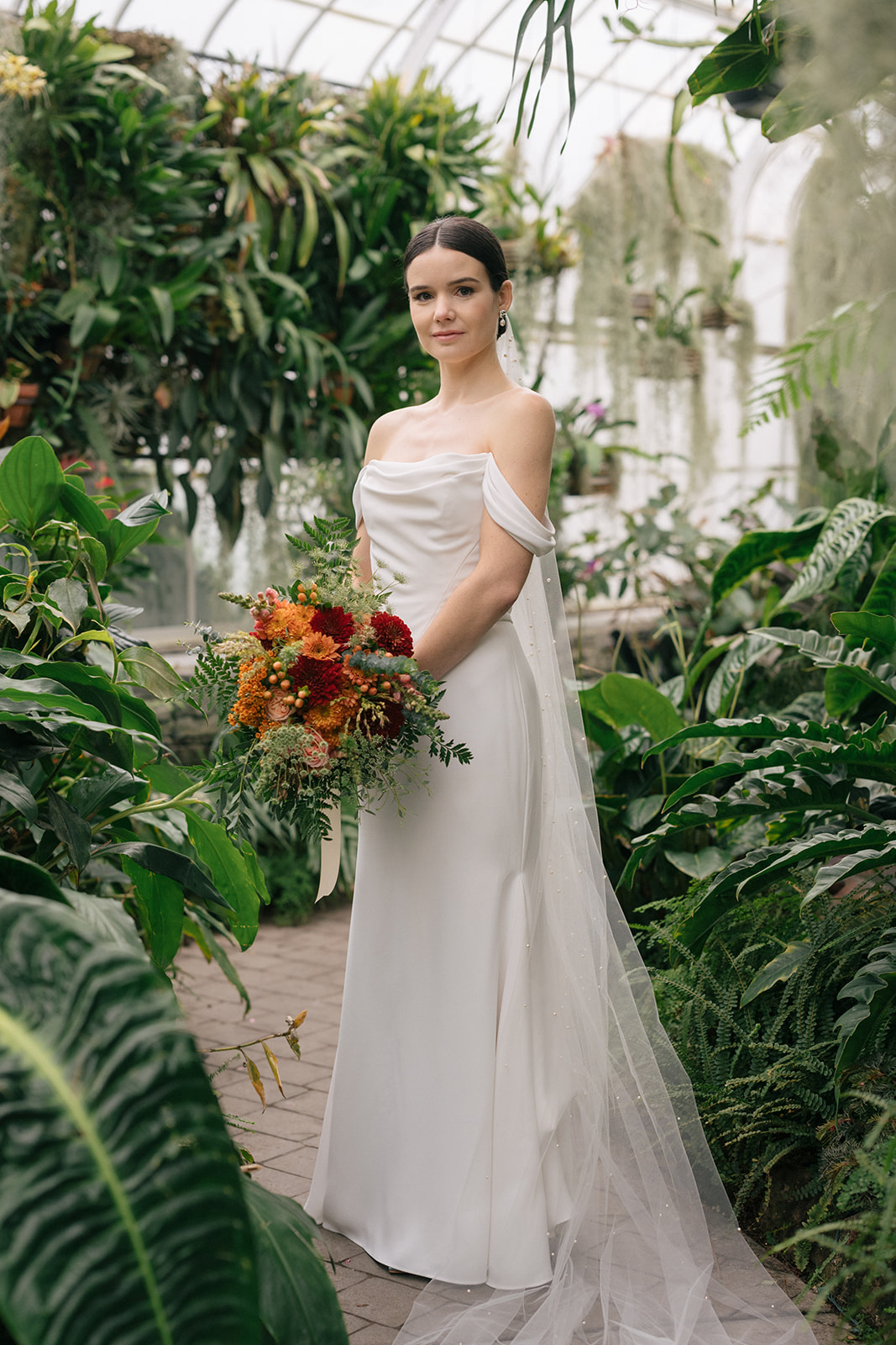 Taylor holding her bouquet while standing in the lush, tropical atmosphere of the Seymour Conservatory.