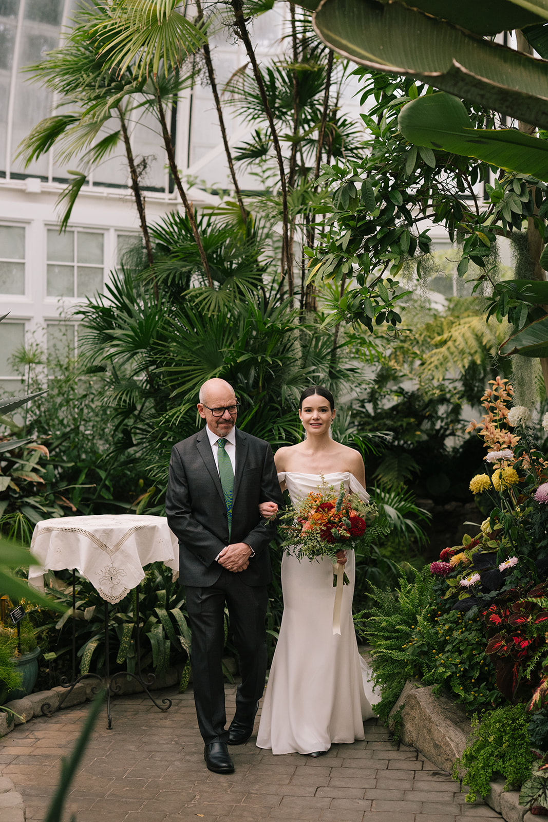 Taylor and her father preparing to walk down the aisle together in the tropical conservatory setting.