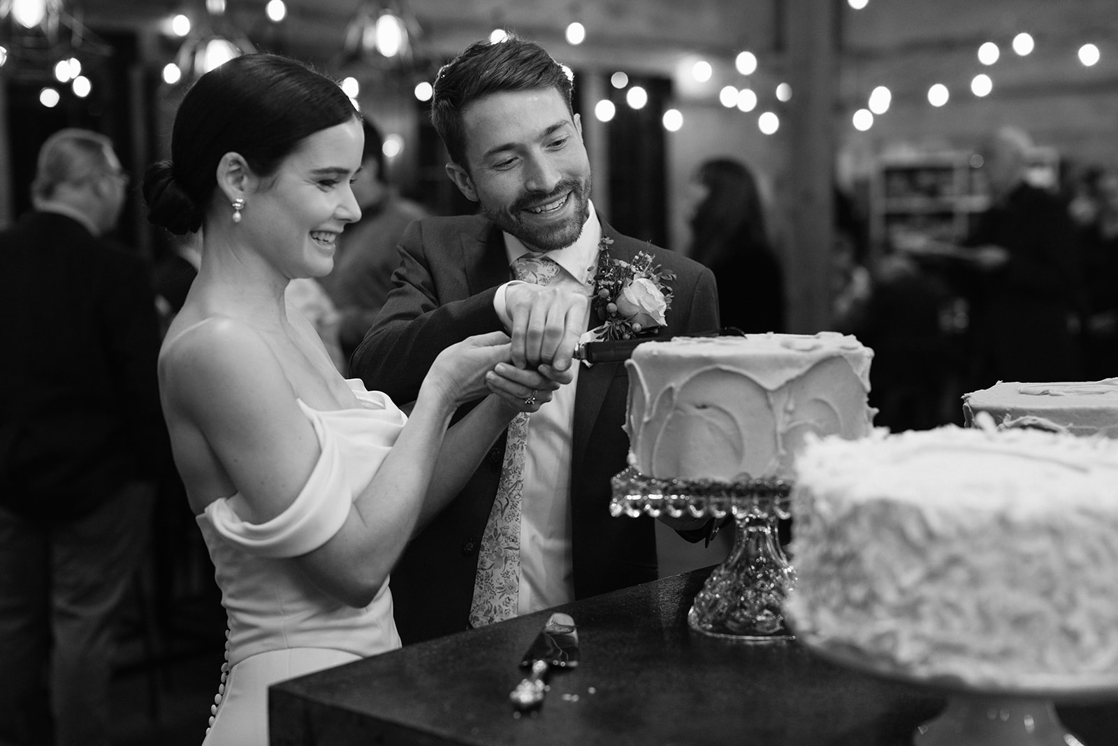 Bride and groom smiling while cutting their wedding cake together.