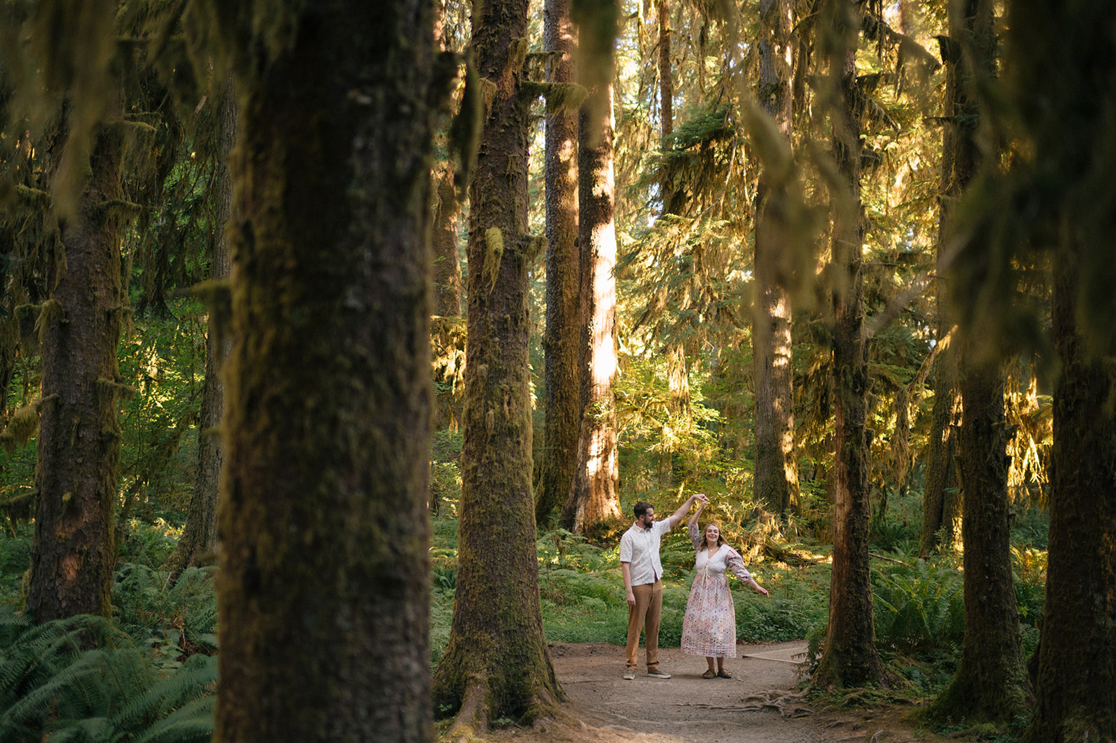 Couple dancing among towering moss-covered old growth trees in the Hoh Rainforest, one of the best places to elope in Washington State, Olympic National Park