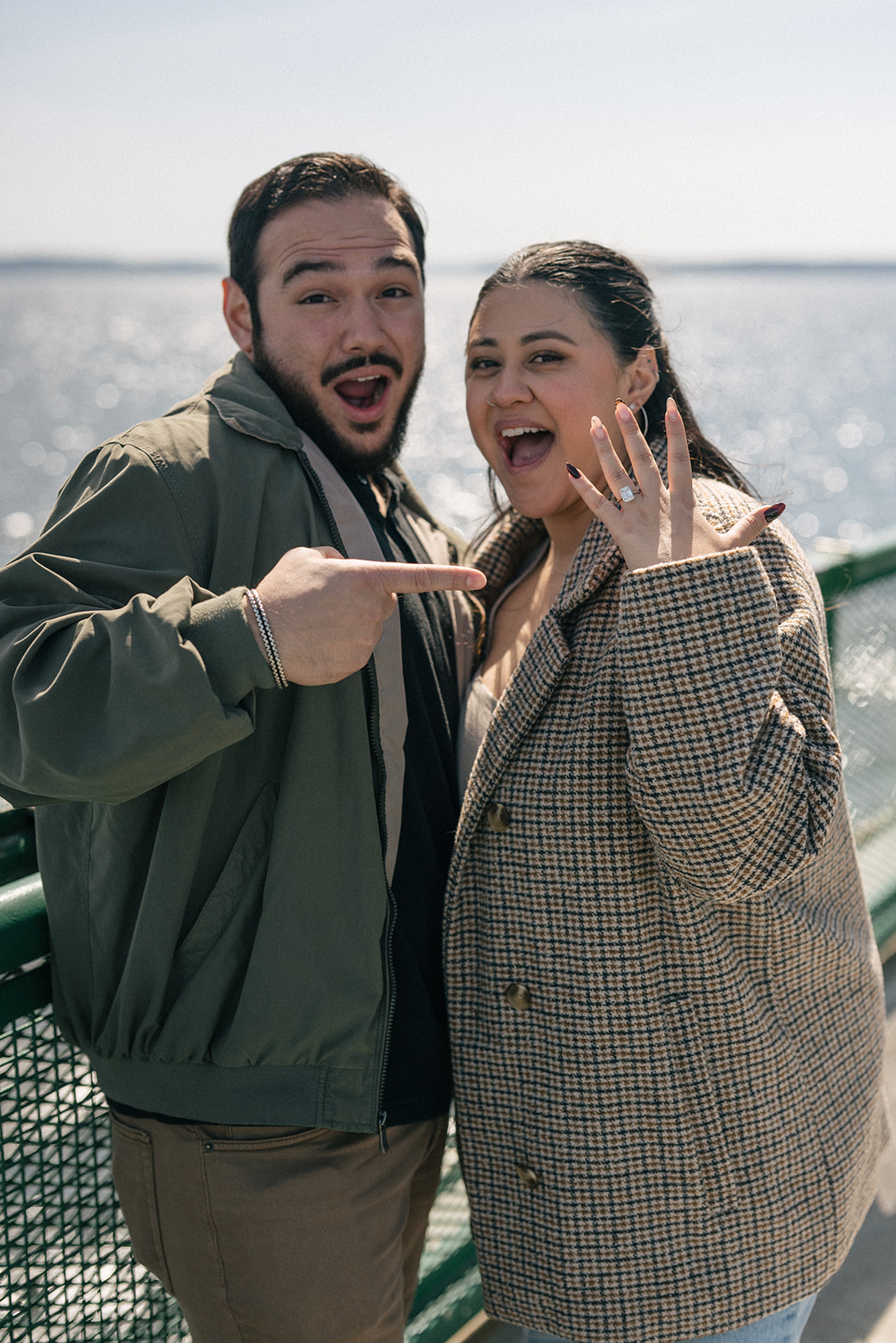 Johnny and Alyssa smile and point at her hand with the new ring