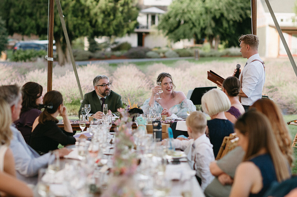 Guests smiling under a canopy during wedding toasts