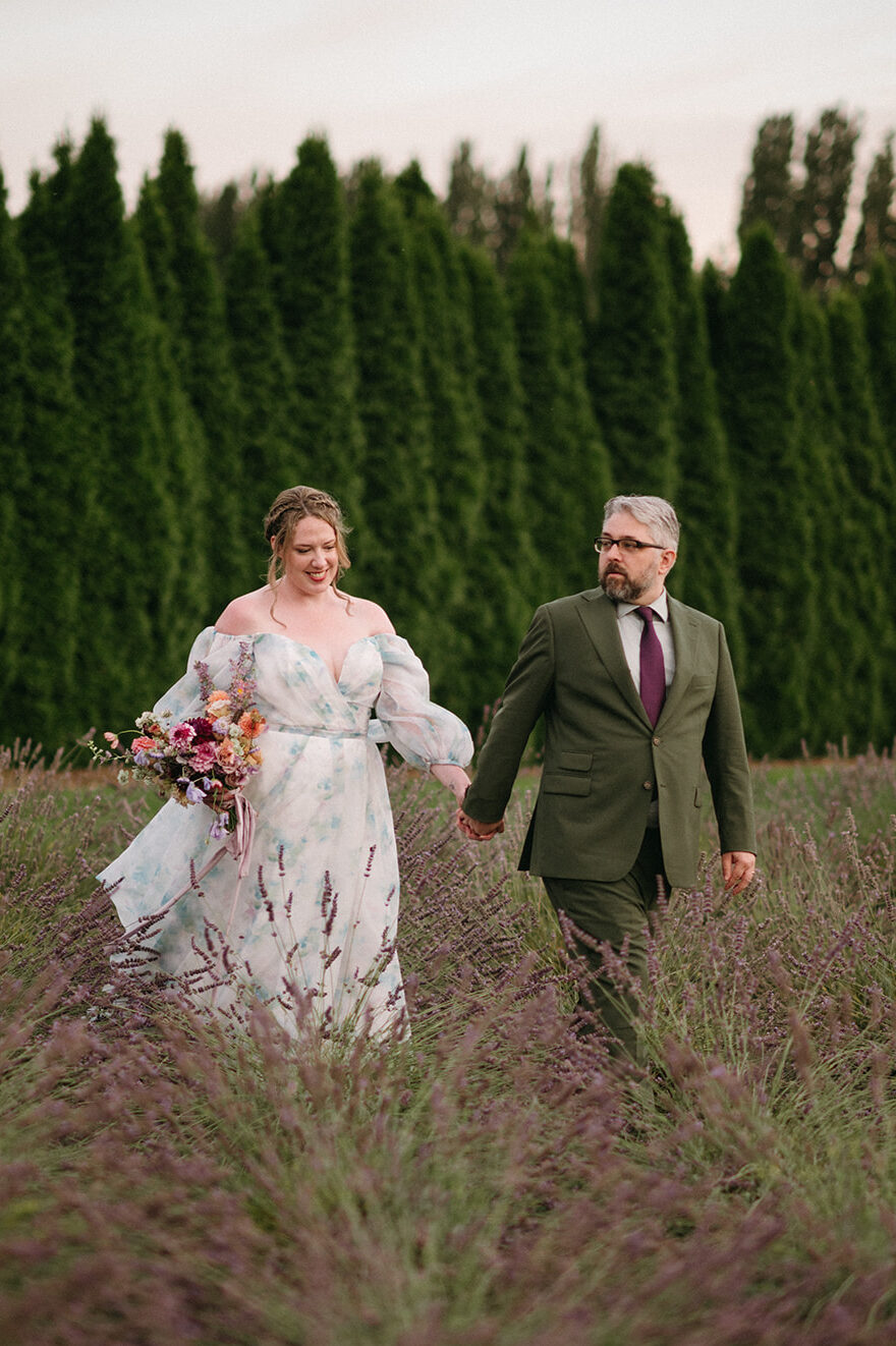 Couple smiling and holding hands while walking through lavender rows
