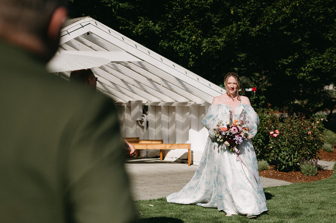 Bride walking down the aisle with bouquet as guests look on