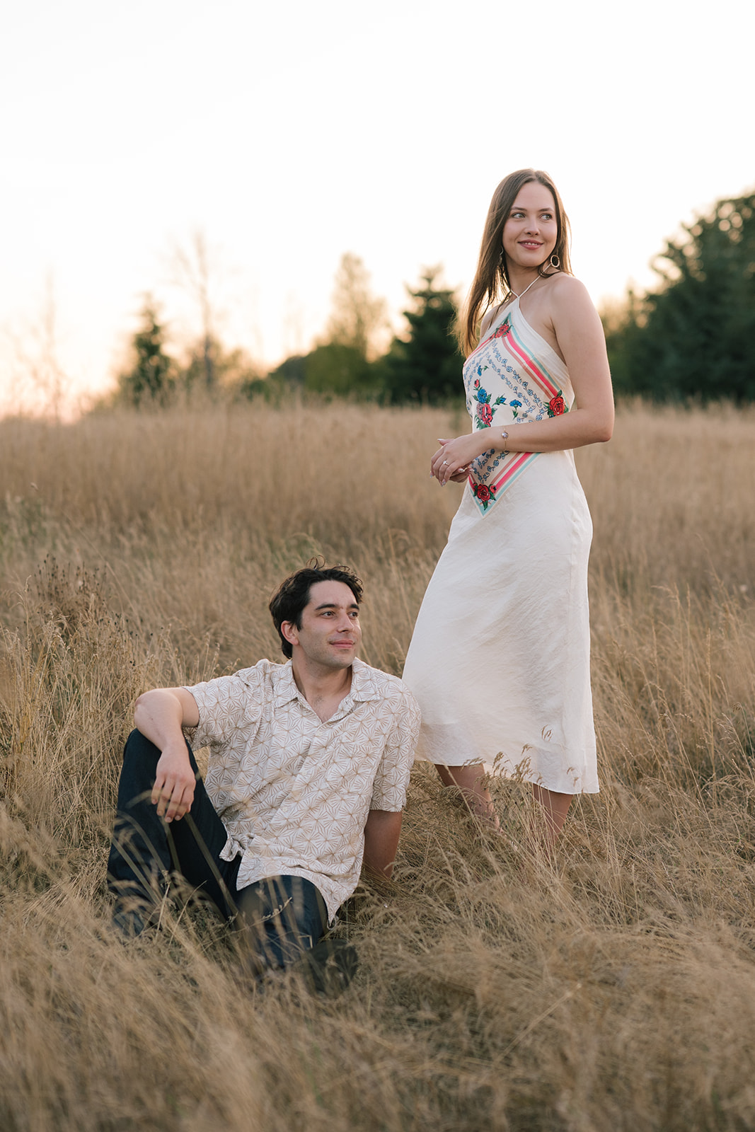 Couple posing in a grassy field.
