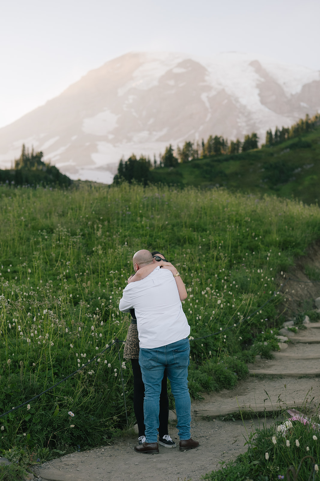Newly engaged couple embraces on the Paradise trail with Mount Rainier rising behind them