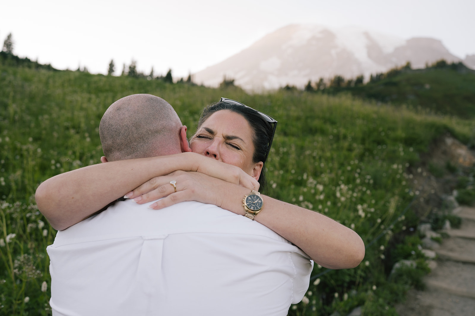 Emotional embrace after a surprise Mount Rainier proposal at Paradise, engagement ring visible on her finger
