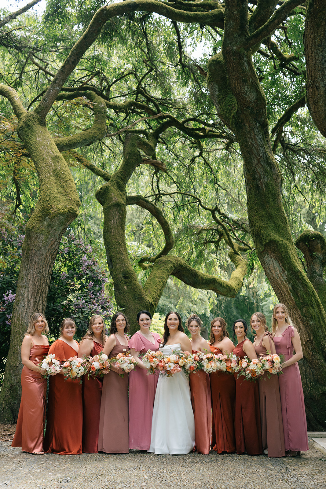 Bridesmaids in mauve dresses holding warm-toned bouquets