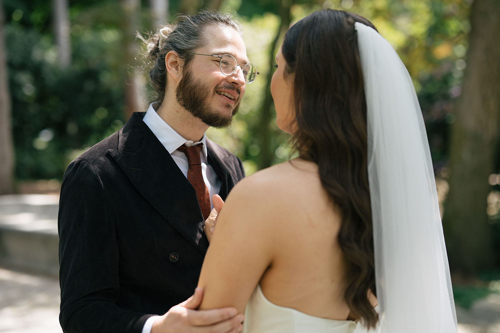 Bride and groom standing beneath towering trees during their Volunteer Park first look