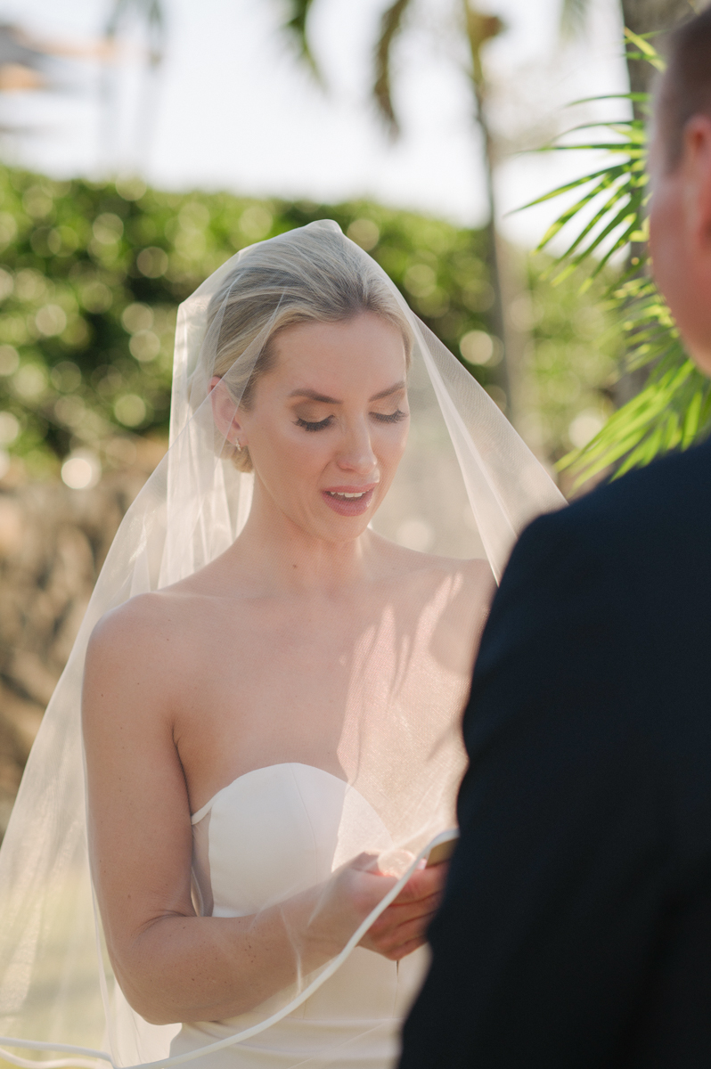 Close-up of the bride reading her personal vows to the groom during their sunset ceremony at Merriman’s Kapalua.