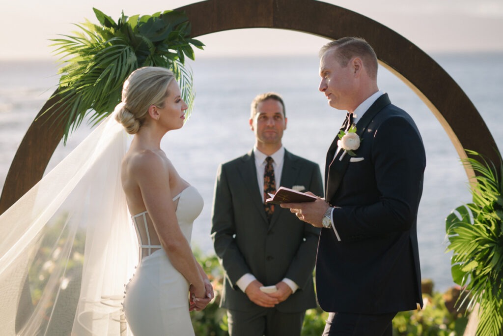 Close-up of the couple facing each other during their ceremony under a circular arch at Merriman’s Kapalua.