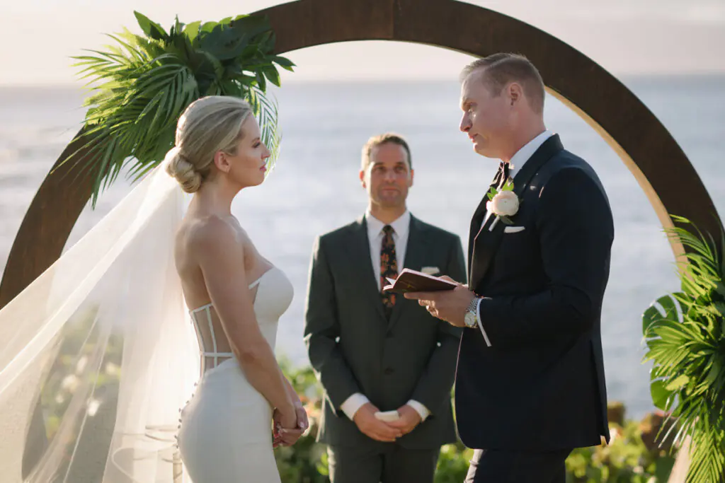 Close-up of the couple facing each other during their ceremony under a circular arch at Merriman’s Kapalua.