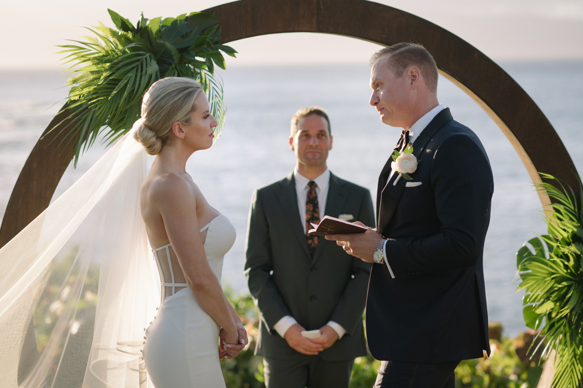 Close-up of the couple facing each other during their ceremony under a circular arch at Merriman’s Kapalua.
