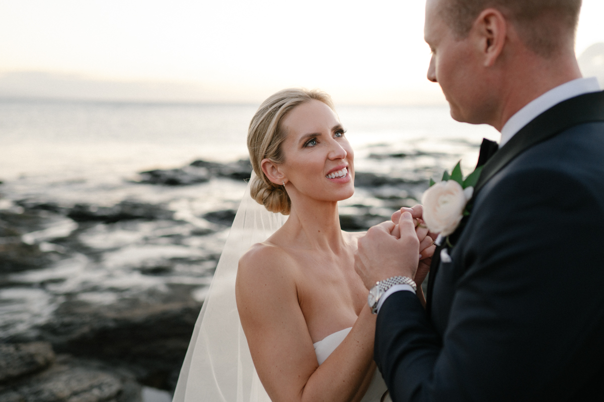 Close-up of the bride and groom holding hands and looking at each other with the ocean in the background in Kapalua.
