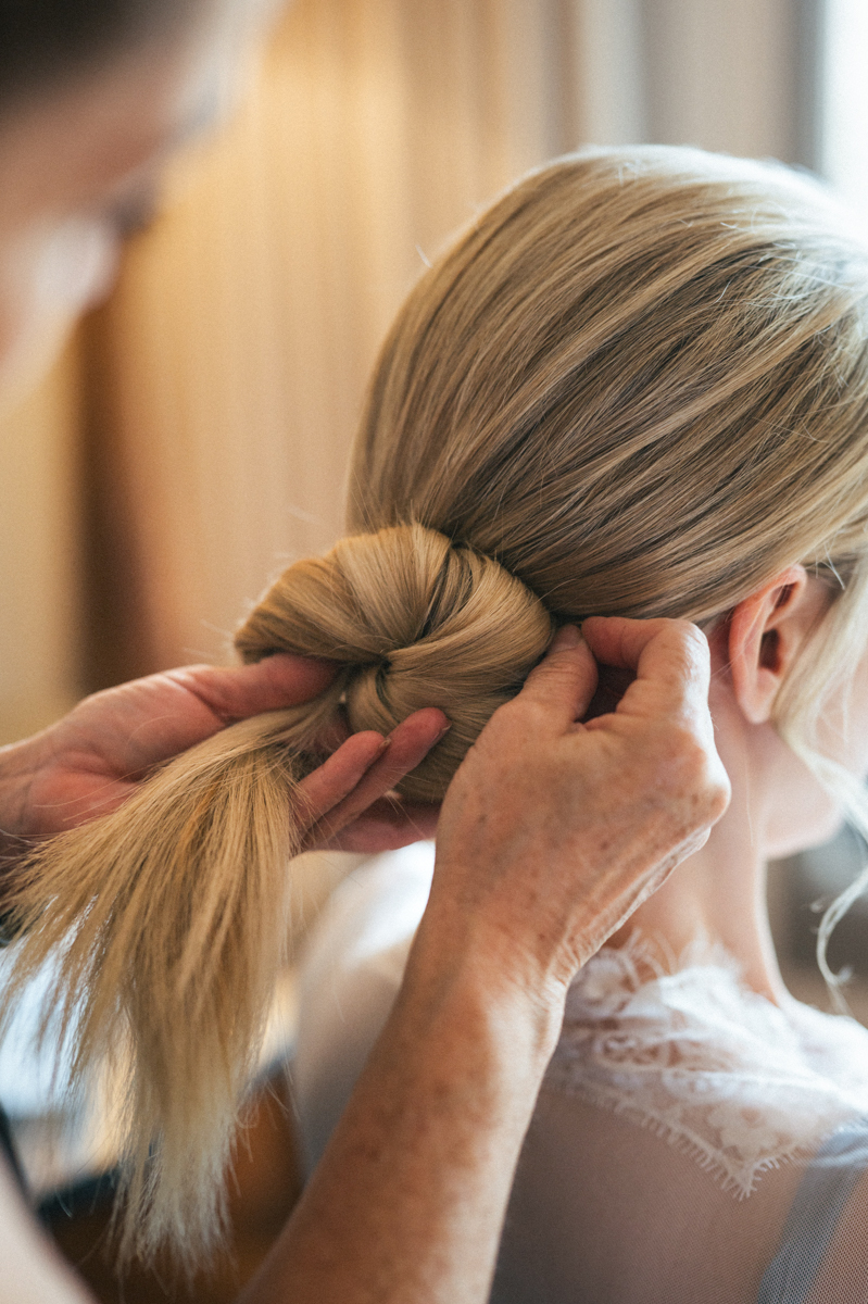 Bride’s hair being styled into a low bun by a hairstylist at the Four Seasons Maui.
