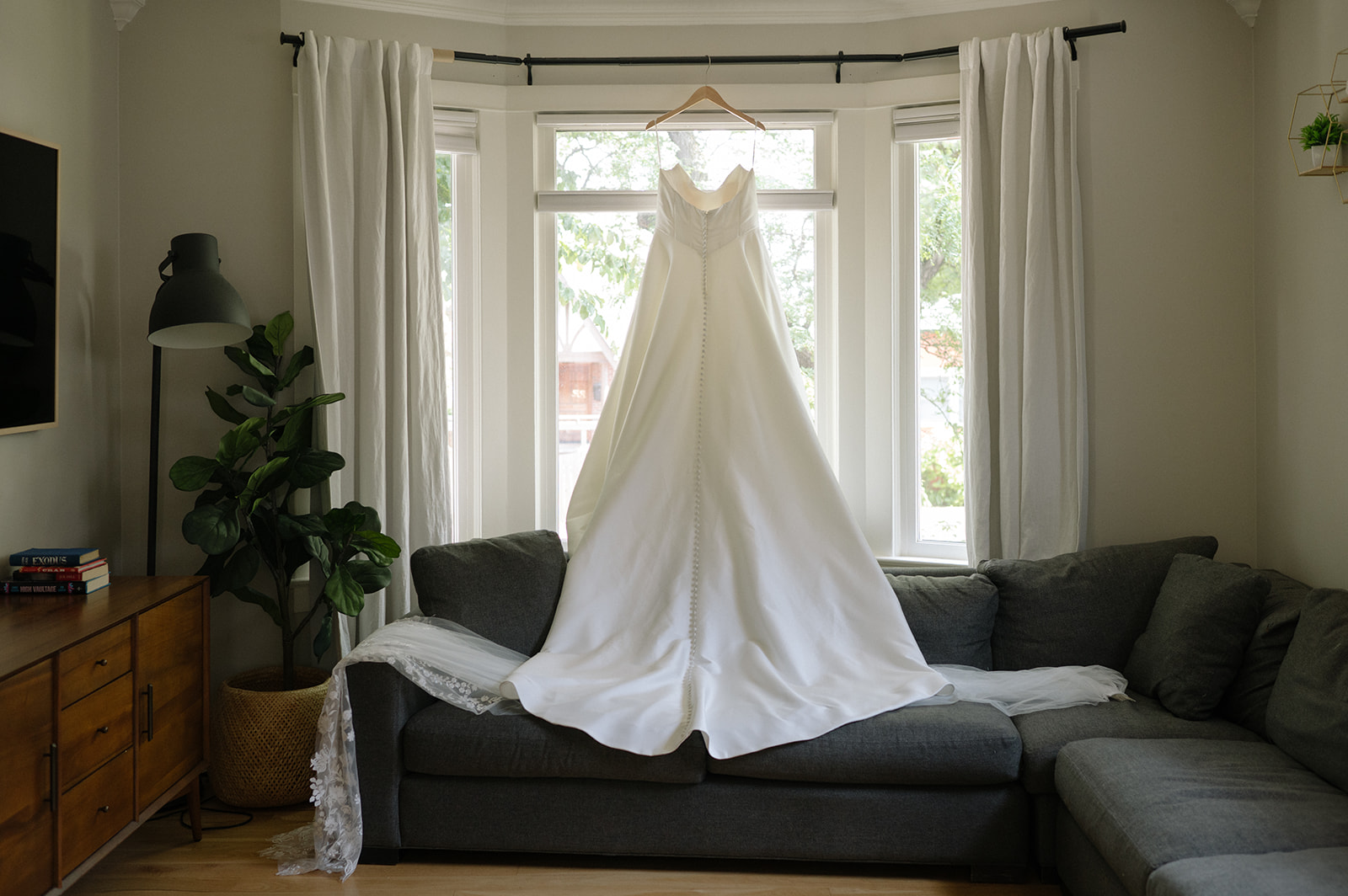 wedding dress hanging in window light before ceremony